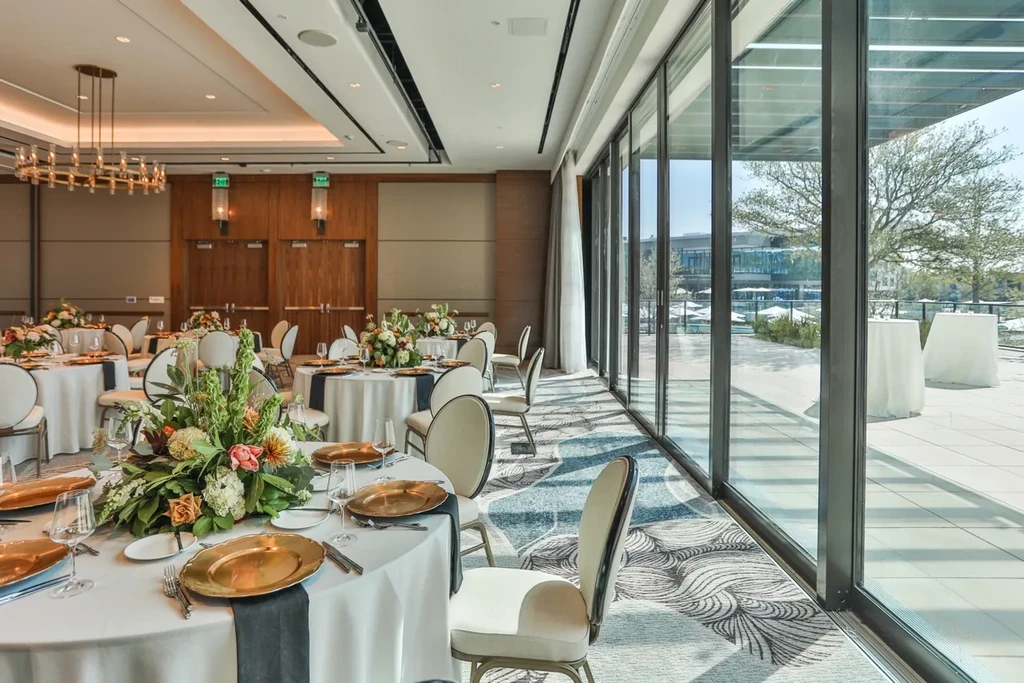 Elegant event hall with formal tables, floral centerpieces, and large windows.