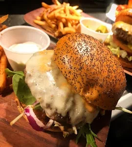 Gourmet hamburger with melted cheese, lettuce, onions on a wooden board.