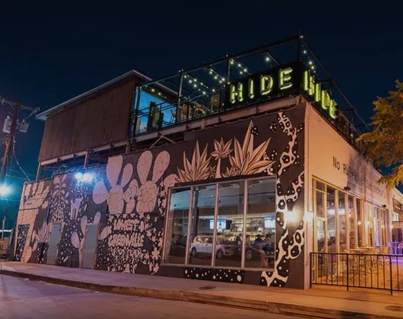 Nighttime restaurant exterior with desert mural, rooftop patio, HIDE HIDE sign.