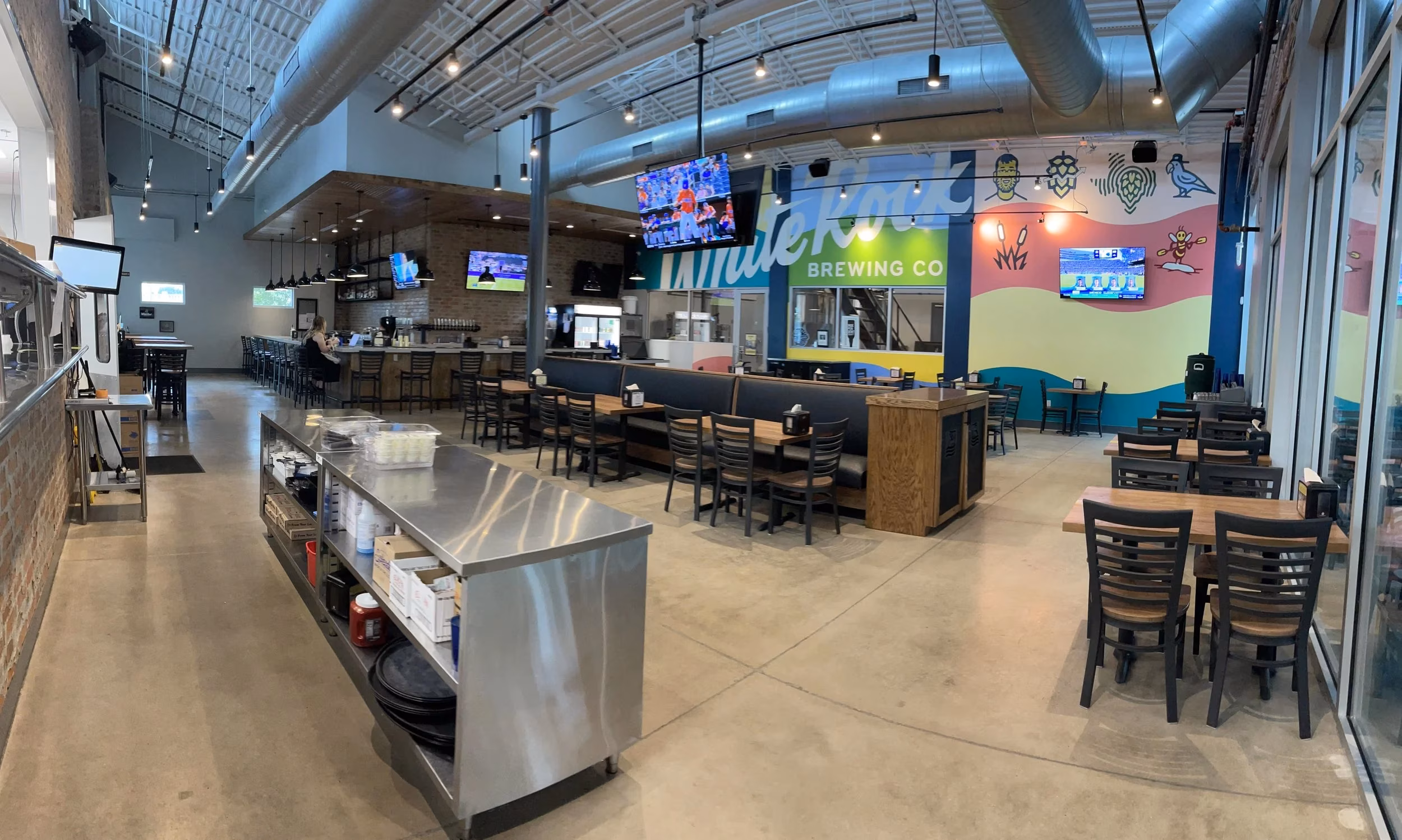 Wide view of White River Brewing Co. interior, bar, tables, and murals.