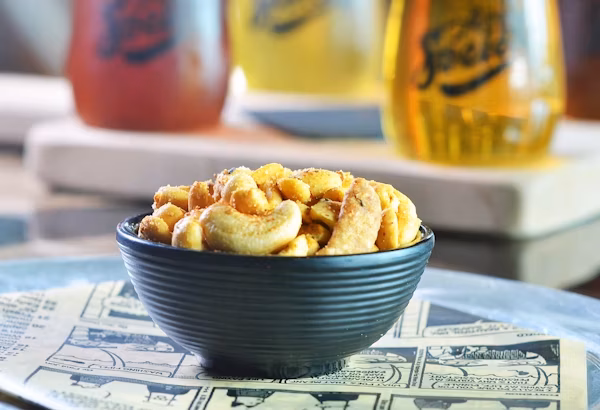 Seasoned cashews in a black bowl on a newspaper.
