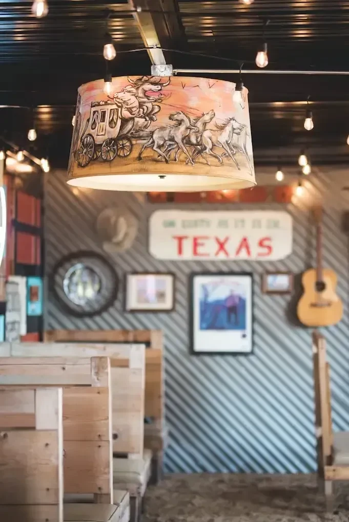 Horse-drawn carriage lampshade in a rustic, Texas-themed restaurant interior.
