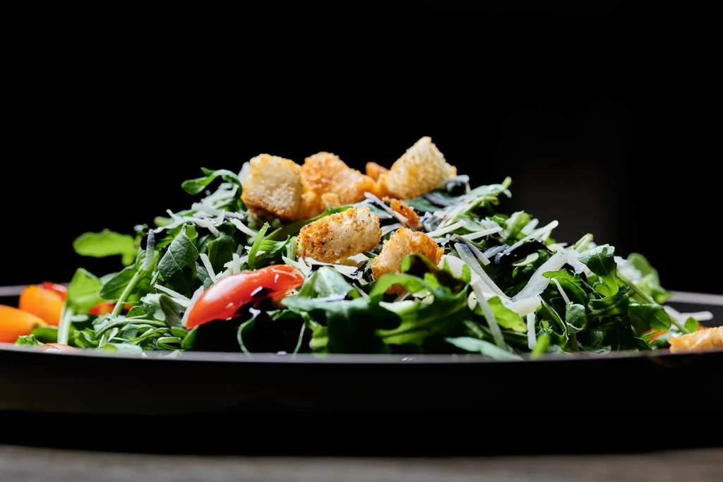 Vibrant green salad with cherry tomatoes, Parmesan, and crispy croutons.