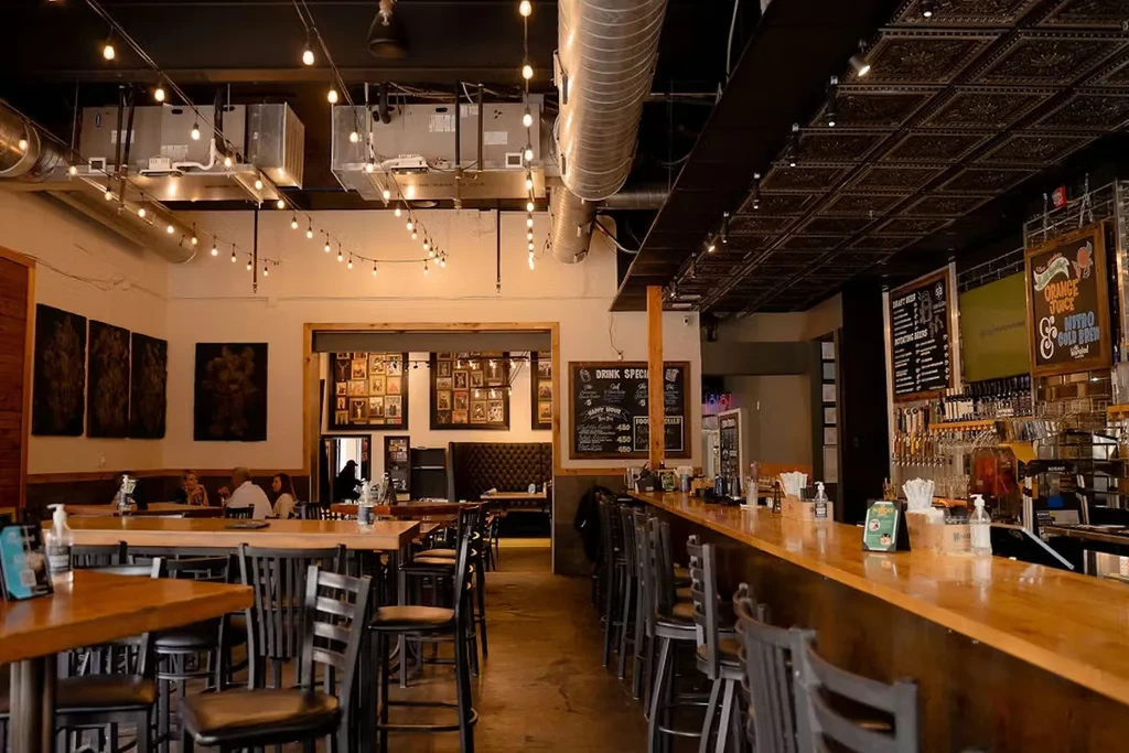 Casual bar interior featuring a long bar, tables, and chalkboard menus.