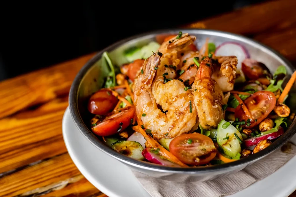 Vibrant shrimp salad with grilled shrimp in a metallic bowl.