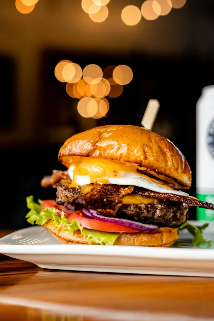 Gourmet burger with a runny fried egg, bacon, and melted cheese.