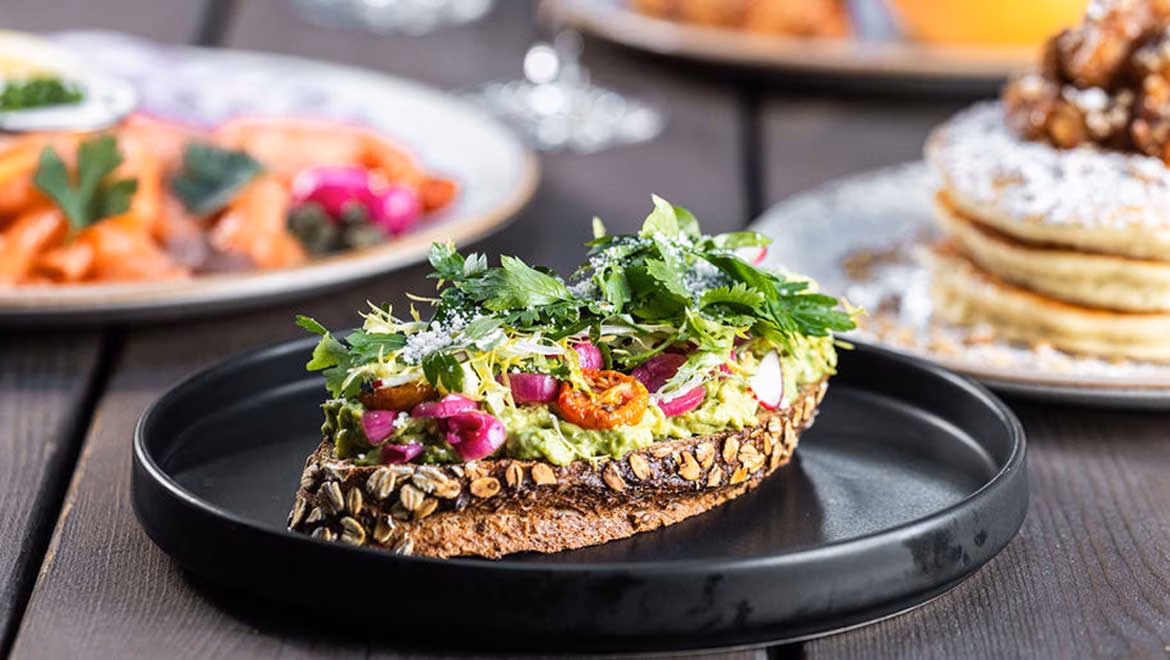 Whole-grain avocado toast with red onion, radish, and greens.