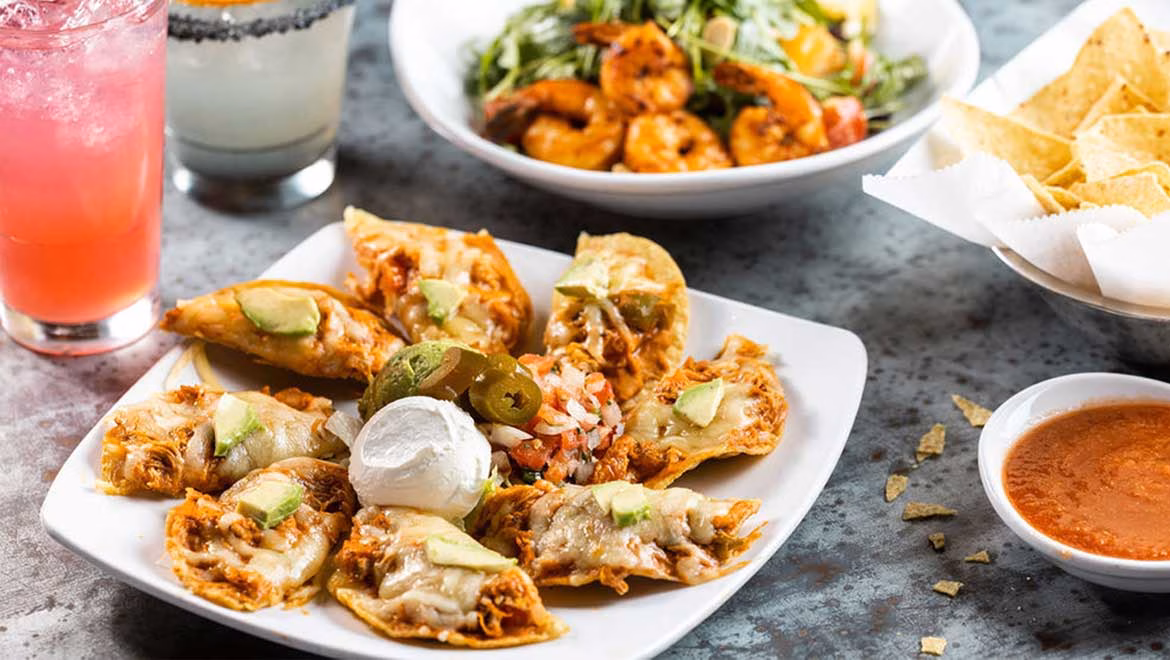 Cheesy chicken tortilla bites with avocado, sour cream, and salsa.