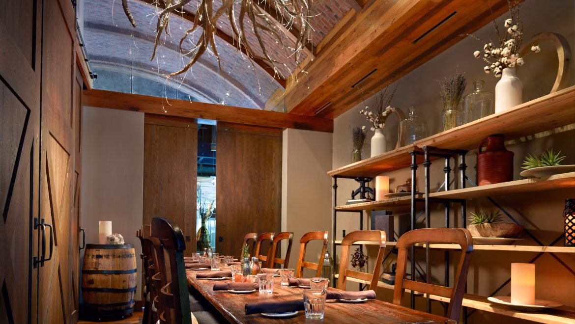 Rustic dining room with long wooden table and decorative shelves.