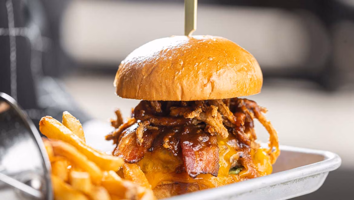 Burger with bacon, crispy fried onions, melted cheese, and fries.
