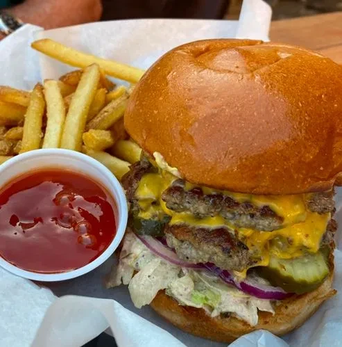 Close-up: double cheeseburger with melted cheese, fries, and ketchup.