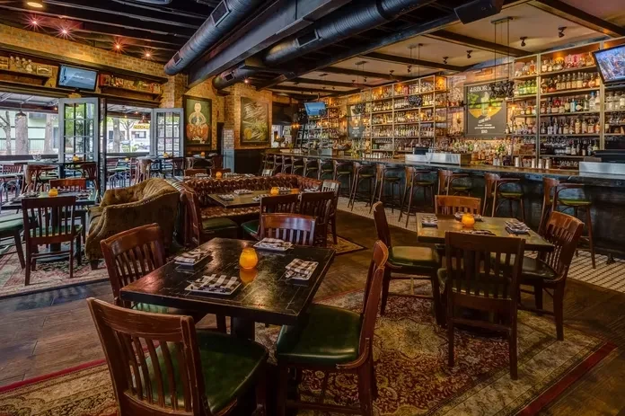 Warm, empty gastropub interior with exposed brick and a well-stocked bar.