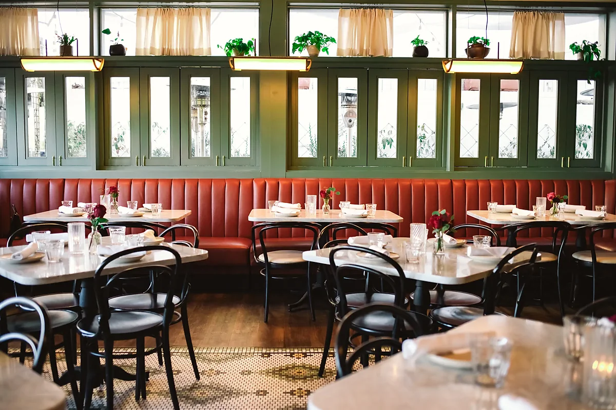 Dining room with red leather banquette, bentwood chairs, green cabinetry