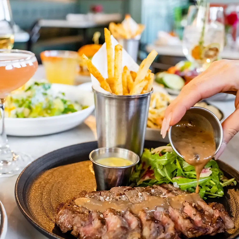 Steak frites with peppercorn sauce poured over sliced filet
