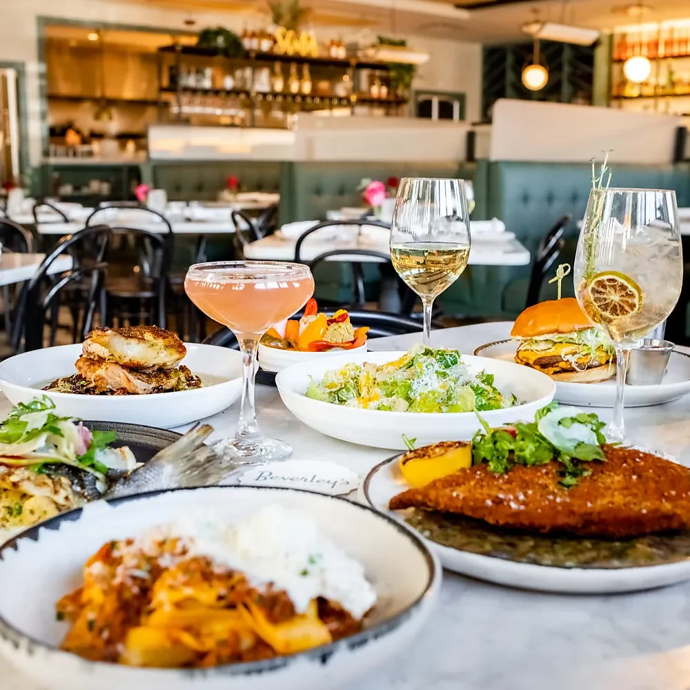 Table of entrees, burger and cocktails in front of bar