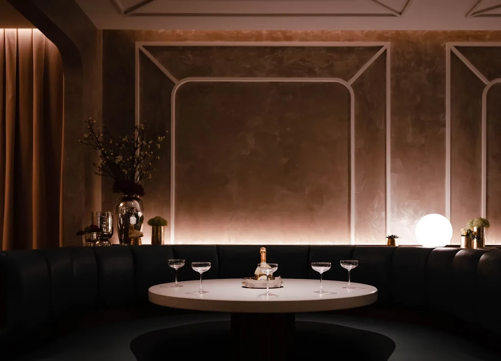 High-end restaurant booth with champagne bottle, five empty glasses.