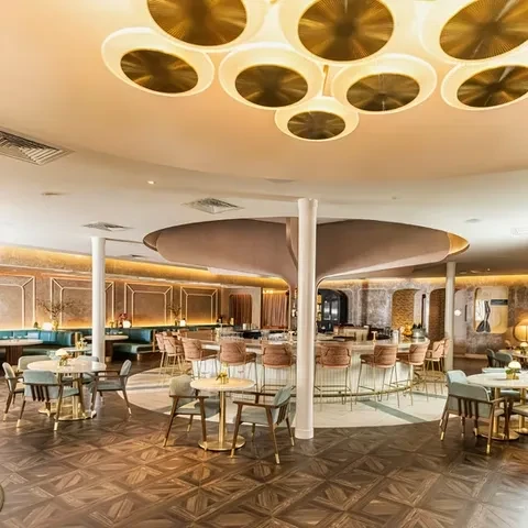 Elegant restaurant interior with circular bar, warm lighting, pink and teal accents.