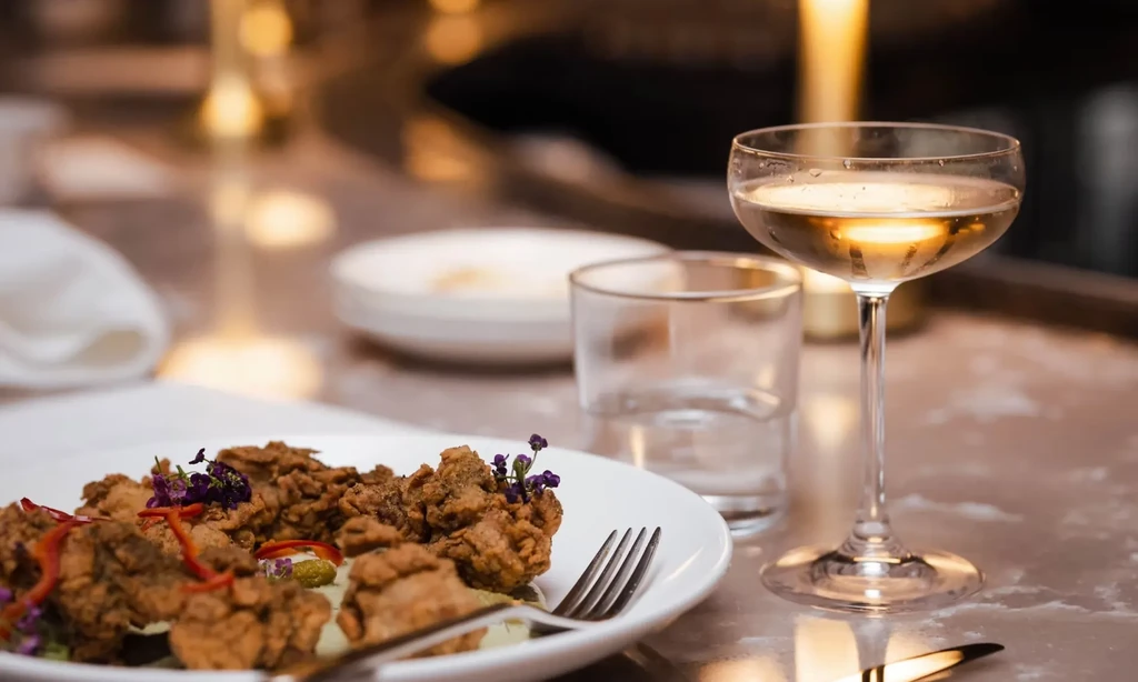 Deep-fried food, cocktail, and empty tumbler on a restaurant table.