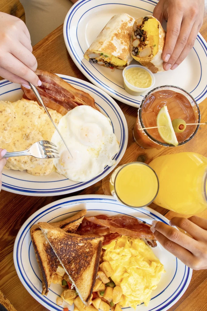 Overhead view: vibrant breakfast and brunch spread with hands.