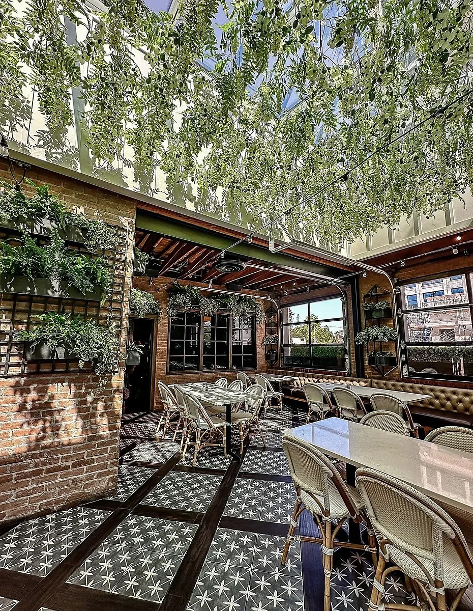 Covered patio with hanging greenery, brick walls, and patterned tile floor