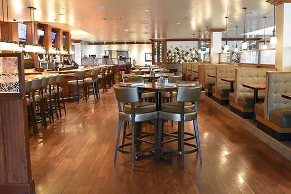 Empty restaurant interior with bar, booths, and high-top tables.