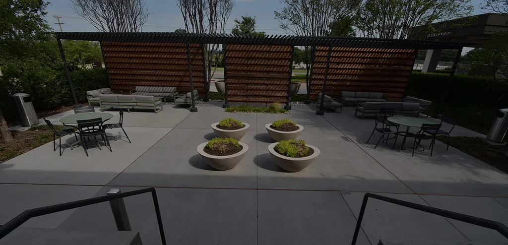 Modern outdoor patio with seating, planters, and pergola structure.
