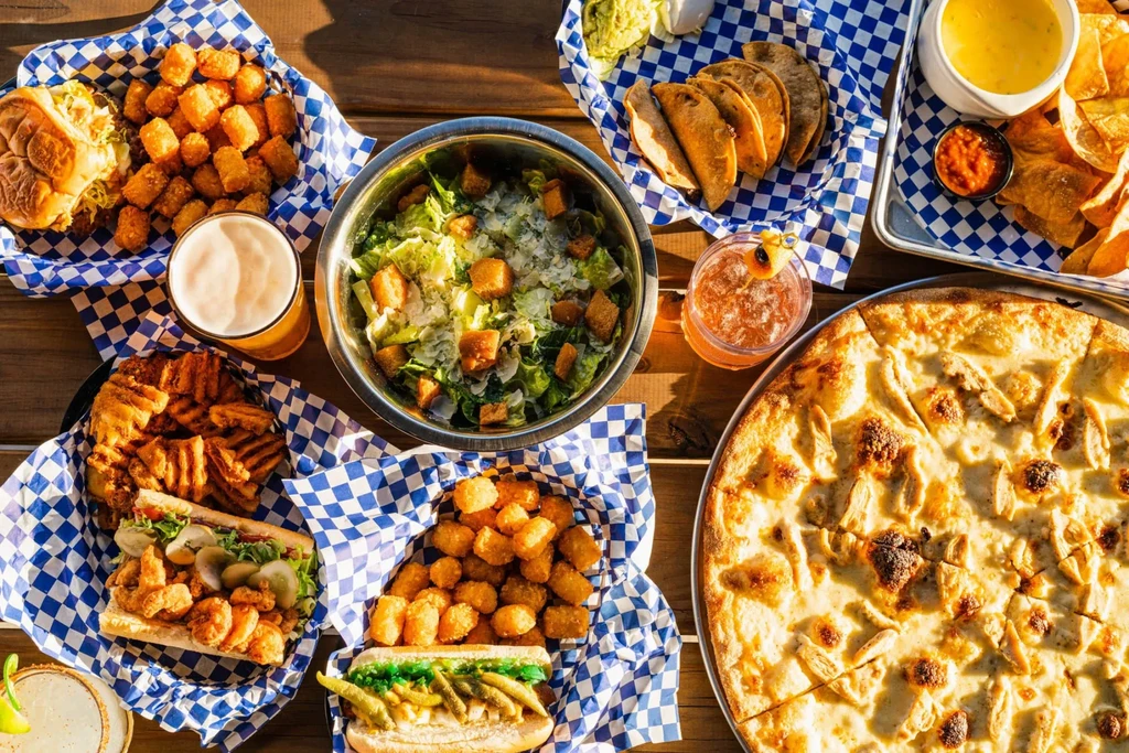 Overhead view of a wooden table laden with diverse food and drinks.