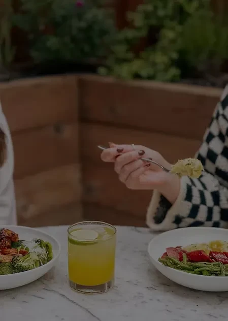 Overhead: Hand eating two plates of food and a layered drink.