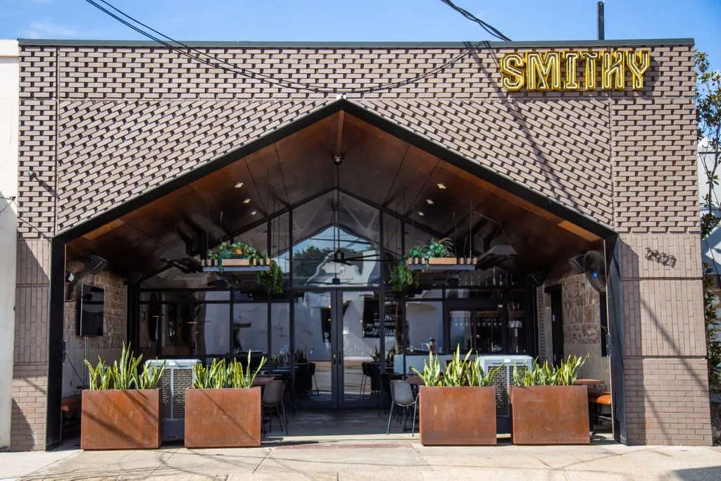 Modern "SMITHY" restaurant with distinctive brick, wood roof, and neon sign.