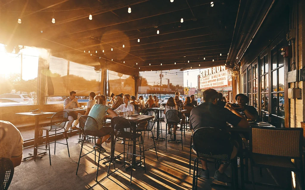 Golden hour patio scene with diners and a 'GRANADA' theater marquee.