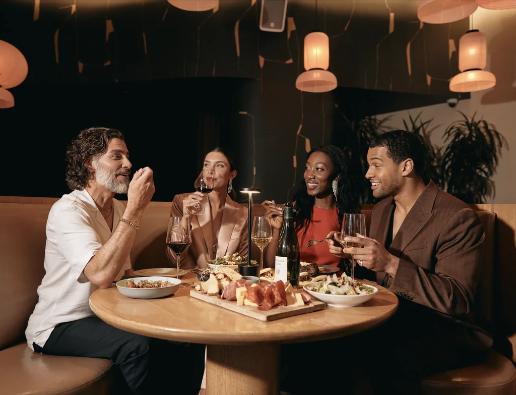 Four adults enjoying food and wine at a sophisticated restaurant.