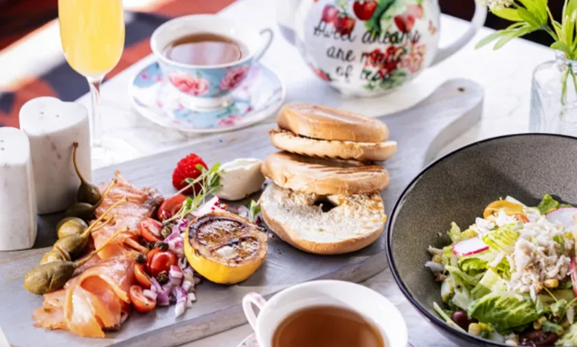 Bright brunch spread with salmon, bagels, salad, tea, and mimosas.