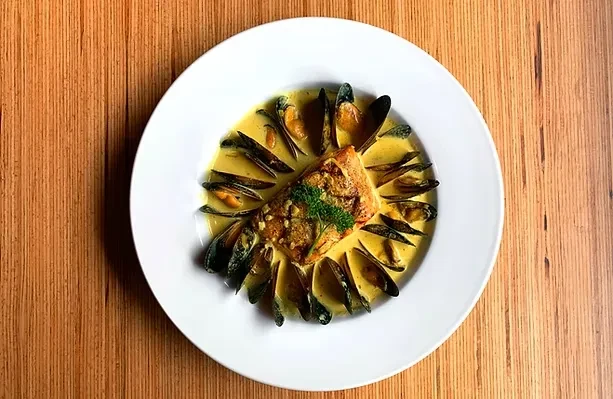 Finely presented pan-seared fish and mussels in creamy sauce.