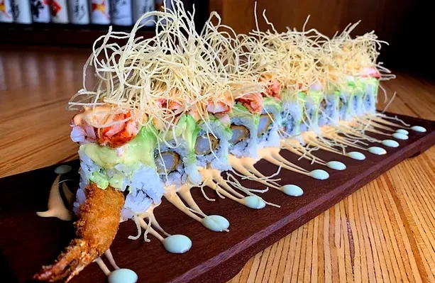 Elaborate sushi rolls with shrimp, avocado, and crispy fried wonton strips topping.