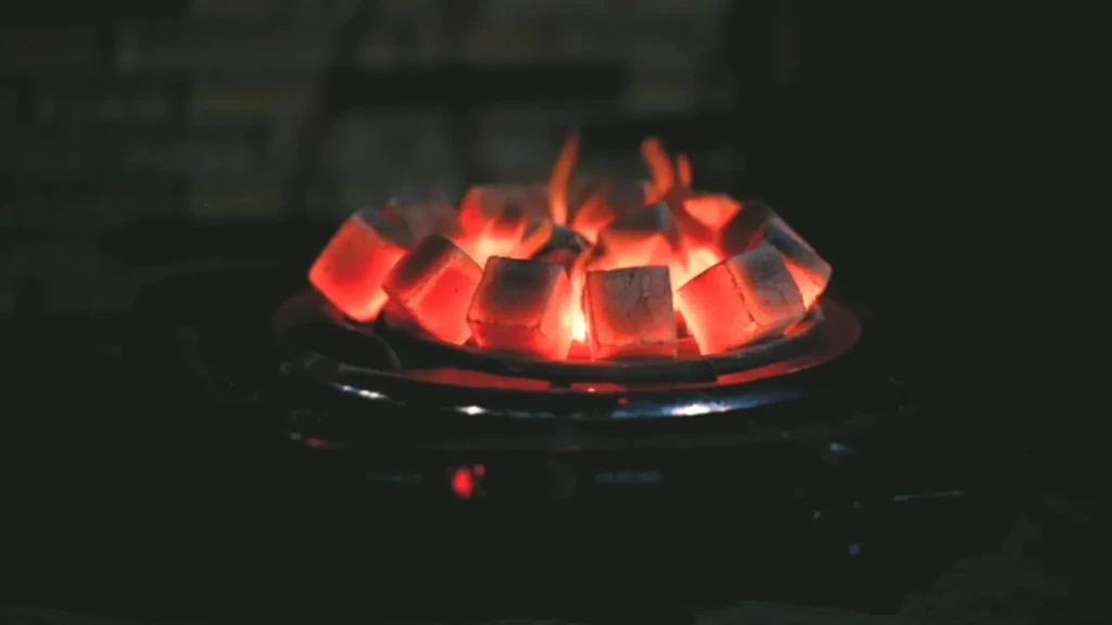 Glowing cubical charcoals arranged circularly on a burner.