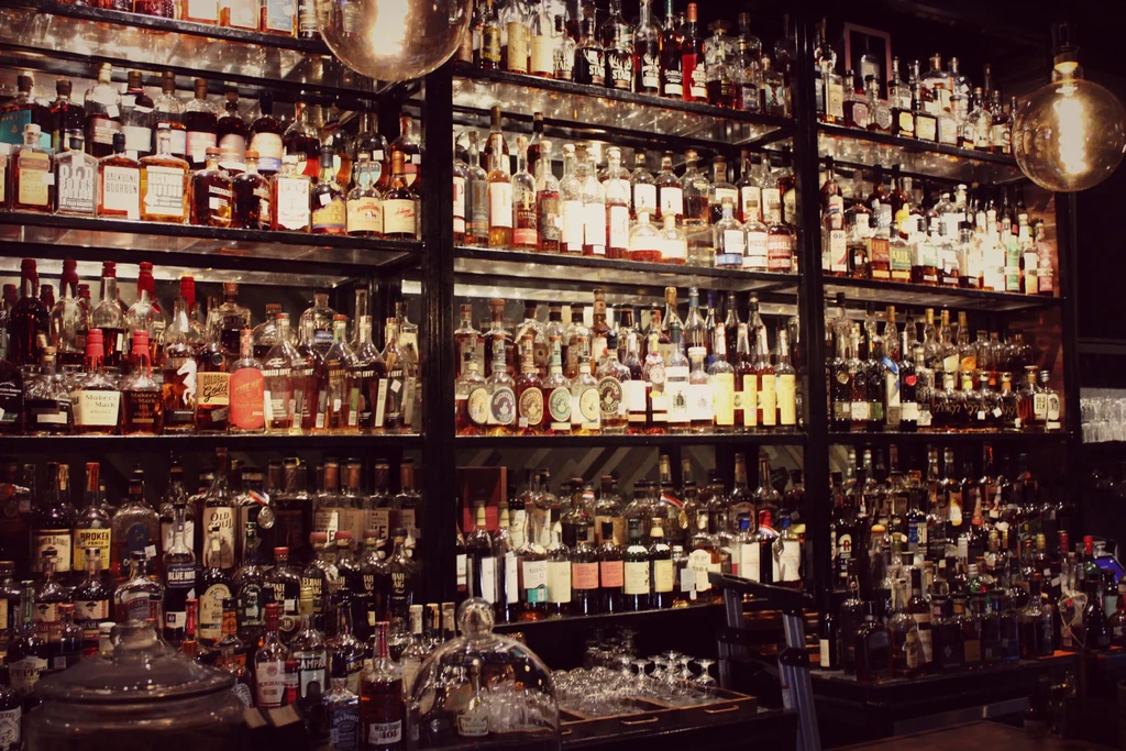 Hundreds of spirit bottles displayed on tall shelves in a dimly lit bar.