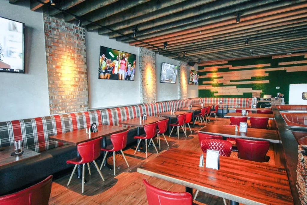 Modern industrial restaurant interior with TVs and plaid booth seating.