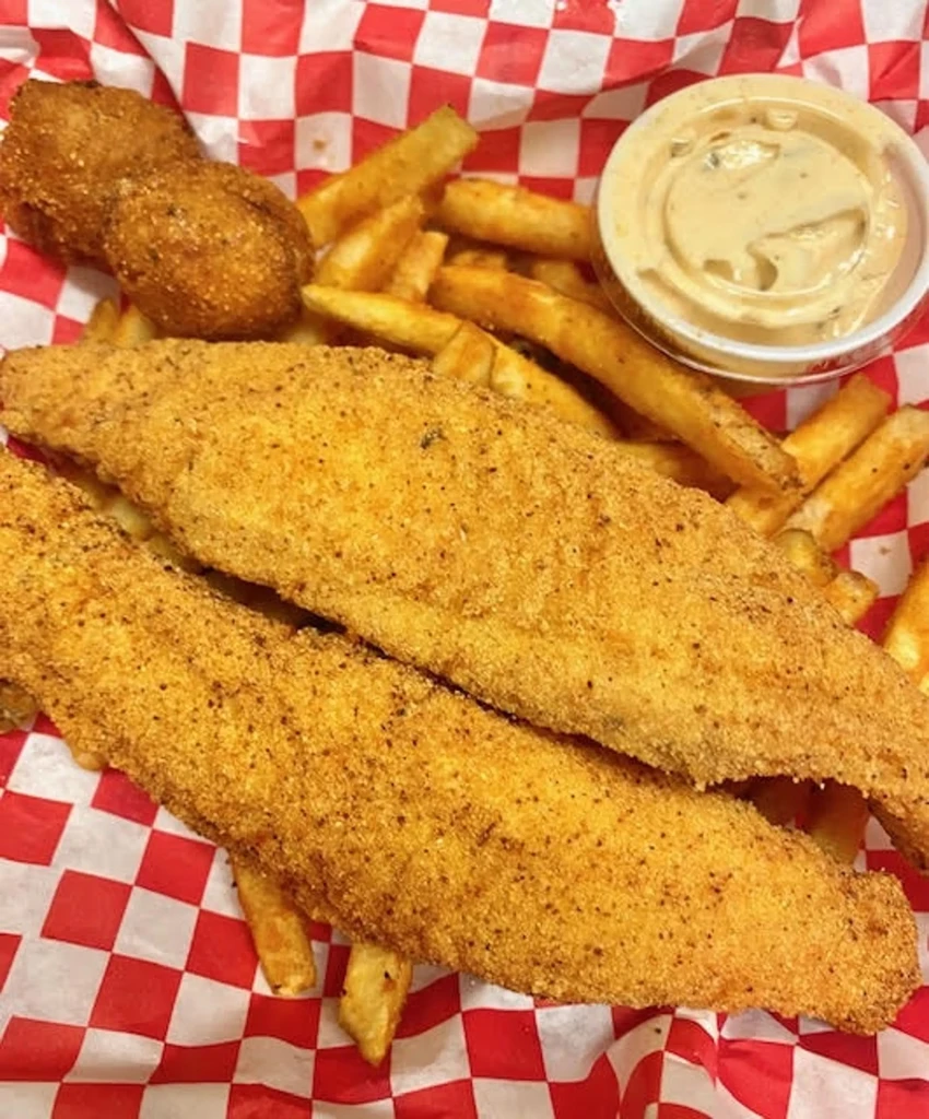 Fried fish fillets, french fries, hush puppies, and dipping sauce.