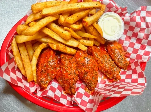 Seasoned fries, buffalo wings, and dipping sauce in a red basket.