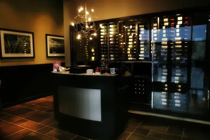 Illuminated wine cellar and modern chandelier in a restaurant interior.