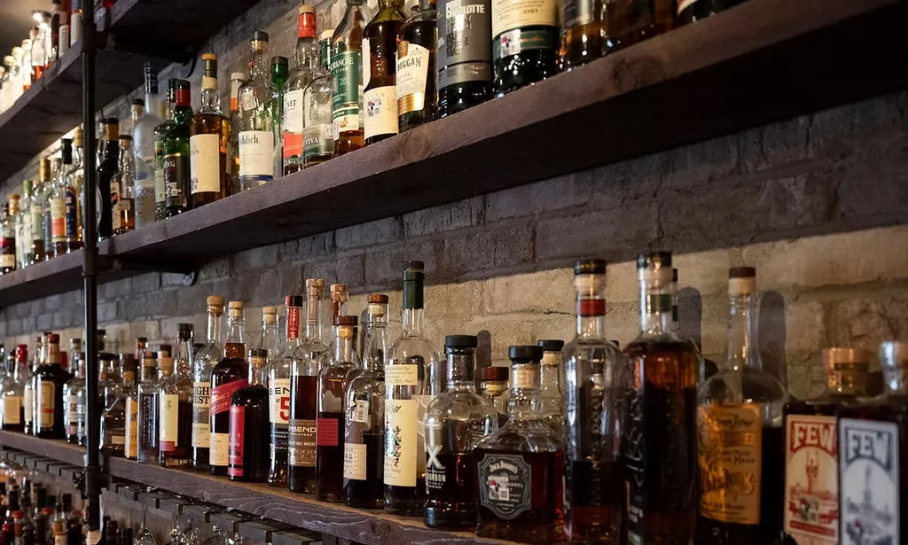 Well-stocked rustic wooden shelves displaying many bottles of spirits.