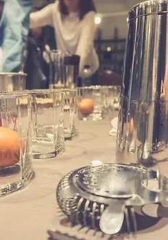 Metal cocktail strainer, shaker, glasses with eggs, person in rustic bar.