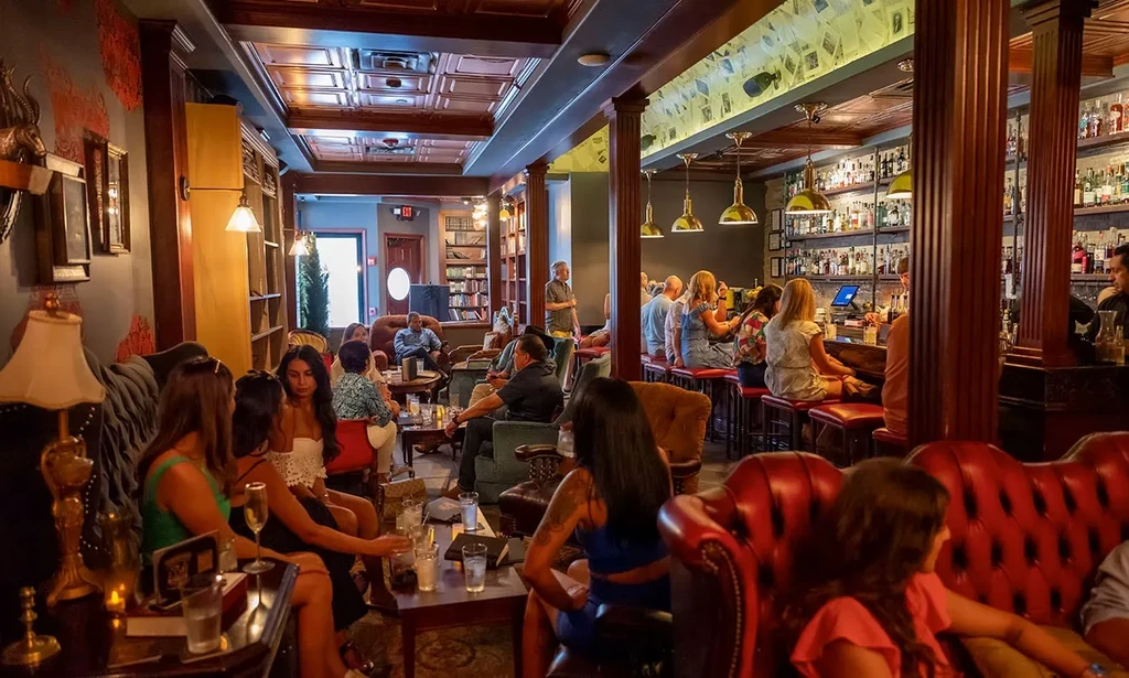Lively, upscale bar with red couches, dark wood, and warm lighting.