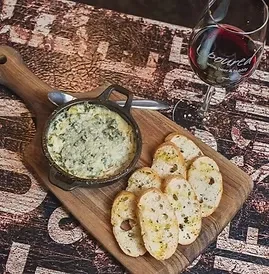 Spinach dip in cast-iron skillet with toasted bread and red wine.