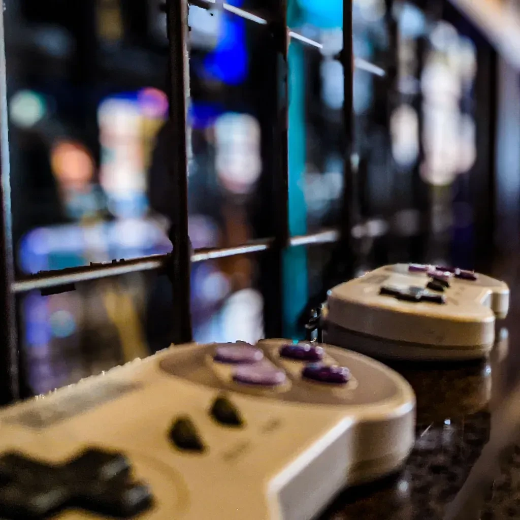 Two vintage SNES controllers on a reflective surface with colorful bokeh.