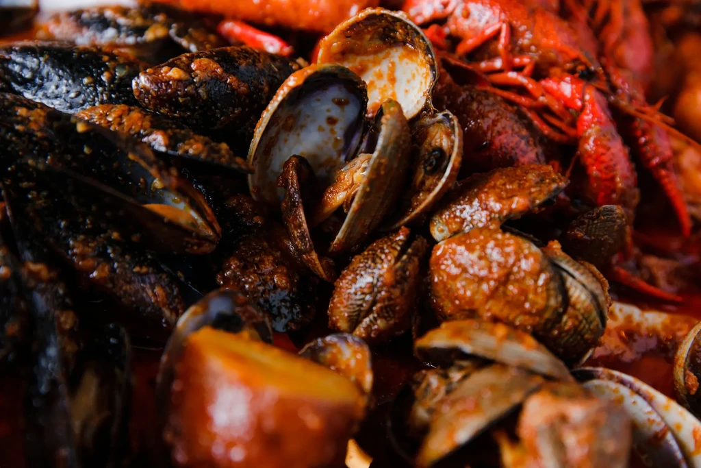 Mussels, clams, crawfish covered in thick reddish-brown sauce.