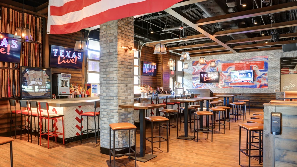 Empty modern sports bar with TVs, baseball bats, and 'TEXAS LIVE!'.