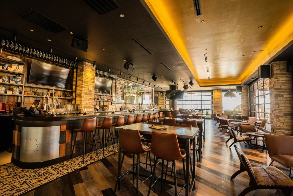 Modern rustic restaurant and bar with visible brewing equipment.