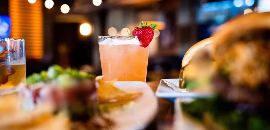 Frothy peach cocktail with strawberry garnish on a restaurant table.