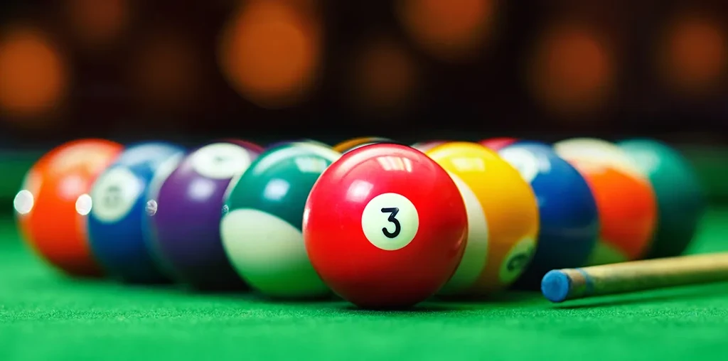 Red '3' billiard ball in focus, racked on green table with cue.